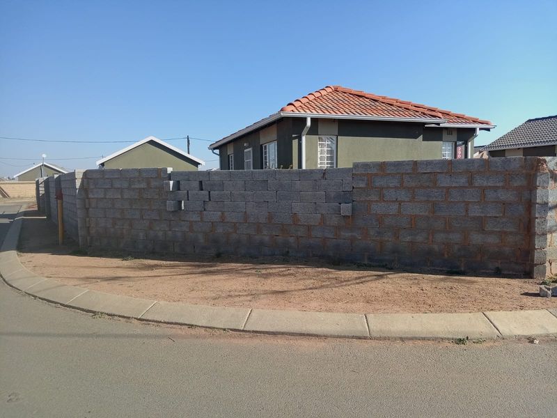 Front exterior view of a residential property featuring a tiled roof and an unfinished concrete block boundary wall.