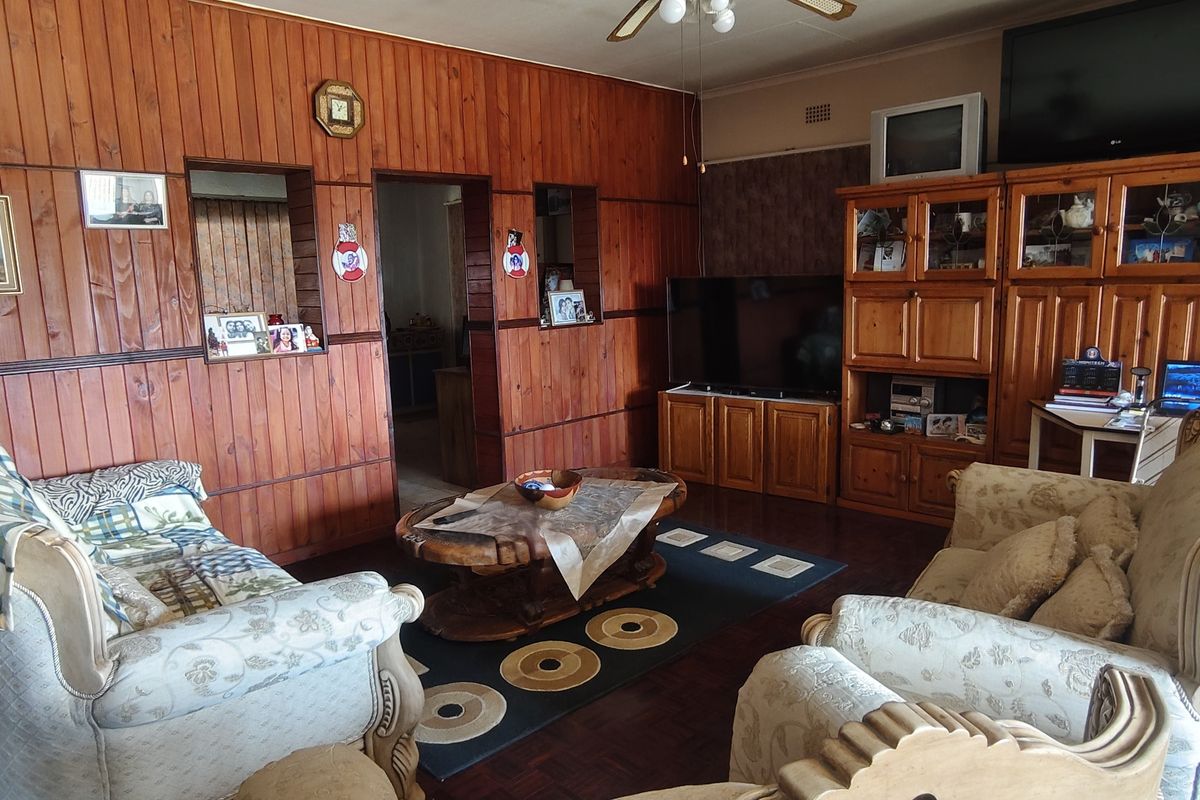 A living room featuring traditional wood paneling, parquet flooring, and built-in cabinetry, offering a dated aesthetic with potential for modernization.
