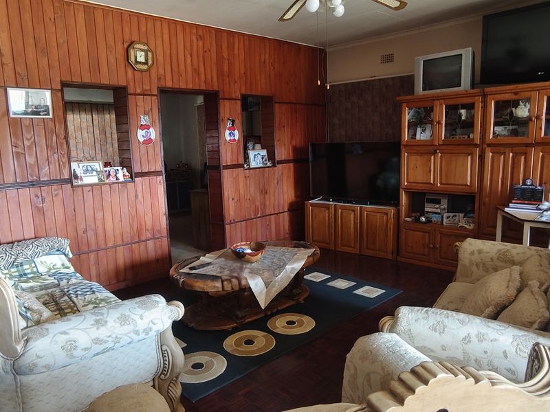A living room featuring traditional wood paneling, parquet flooring, and built-in cabinetry, offering a dated aesthetic with potential for modernization.