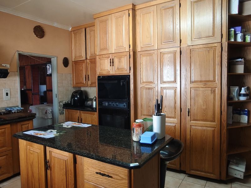 A traditional kitchen featuring extensive wooden cabinetry, granite countertops, a central island, and built-in appliances, offering a functional layout with classic finishes.