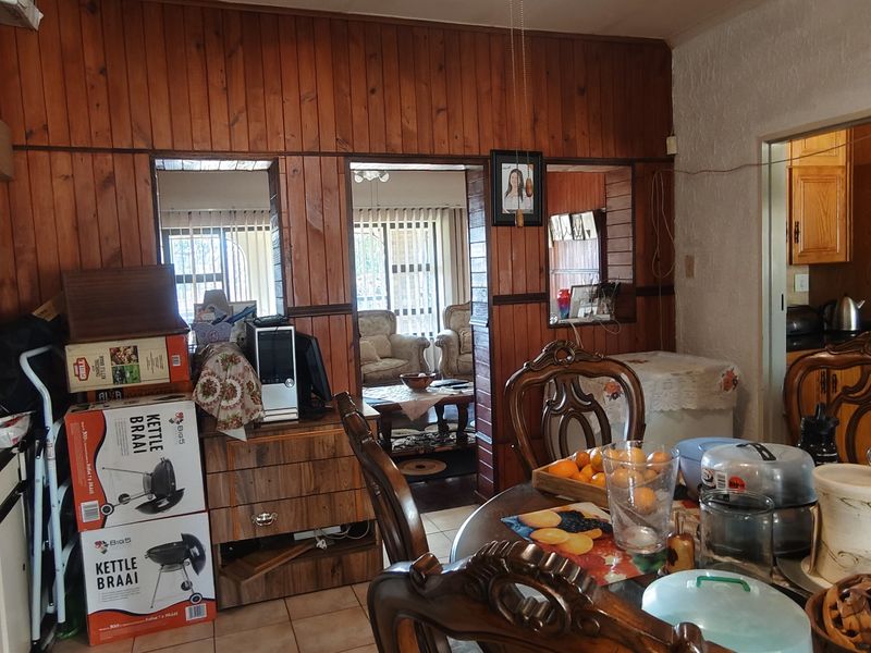 Dining area featuring wood-paneled walls and a pass-through window connecting to the adjacent living space and kitchen.