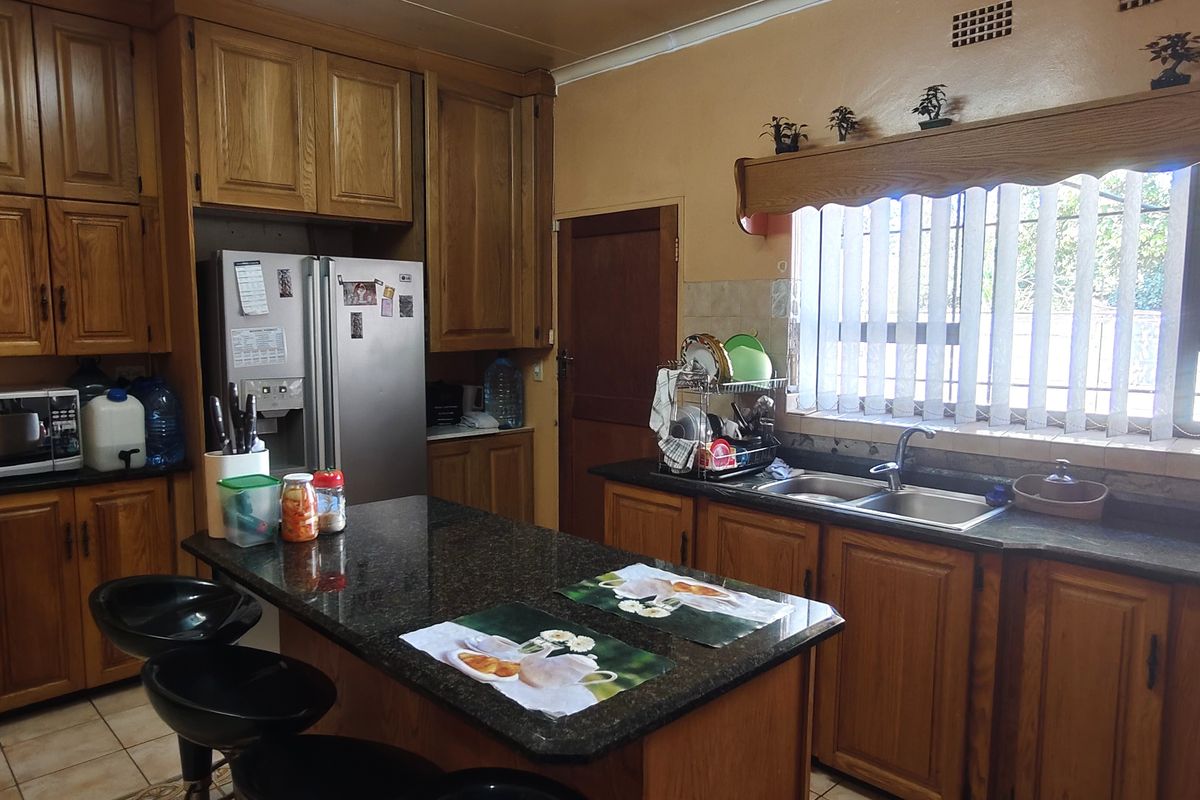 A traditional kitchen featuring wooden cabinetry, granite countertops, a central island, and a double basin sink with natural light from the window.