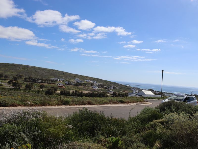 A scenic view of the coastal landscape, featuring a paved road, surrounding hills, and distant ocean views.