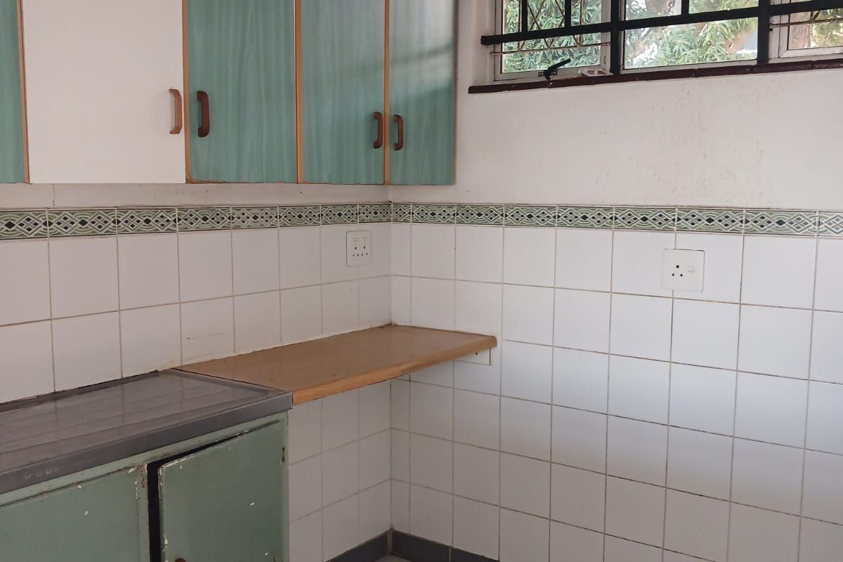 A functional kitchen space featuring built-in cabinetry, tiled splashbacks, and tiled flooring, ready for a modern renovation to update the dated finishes.