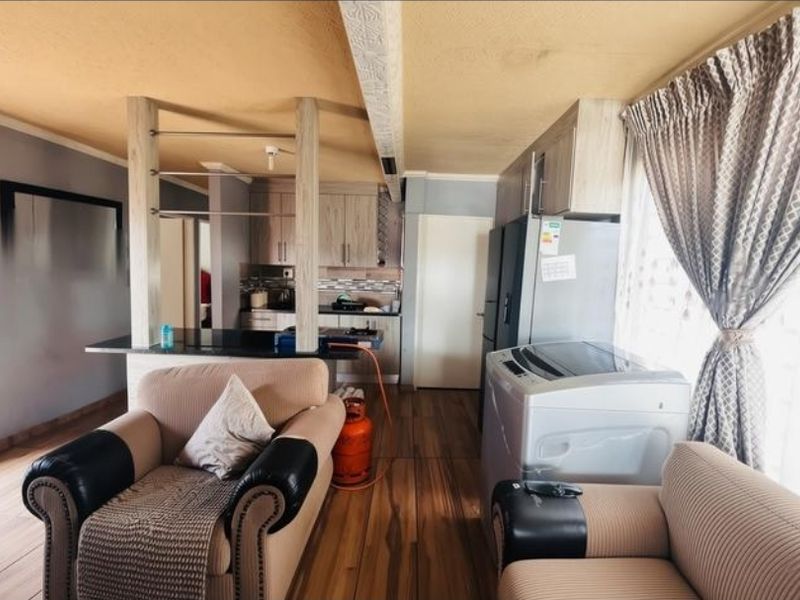 Open-plan living and kitchen area featuring laminate flooring, built-in cabinetry, and a breakfast bar, offering a functional layout for daily living.