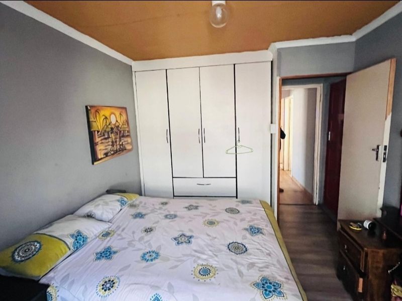 A bedroom featuring built-in wardrobes, laminate flooring, and a neutral wall color, providing a functional space with potential for cosmetic updates.