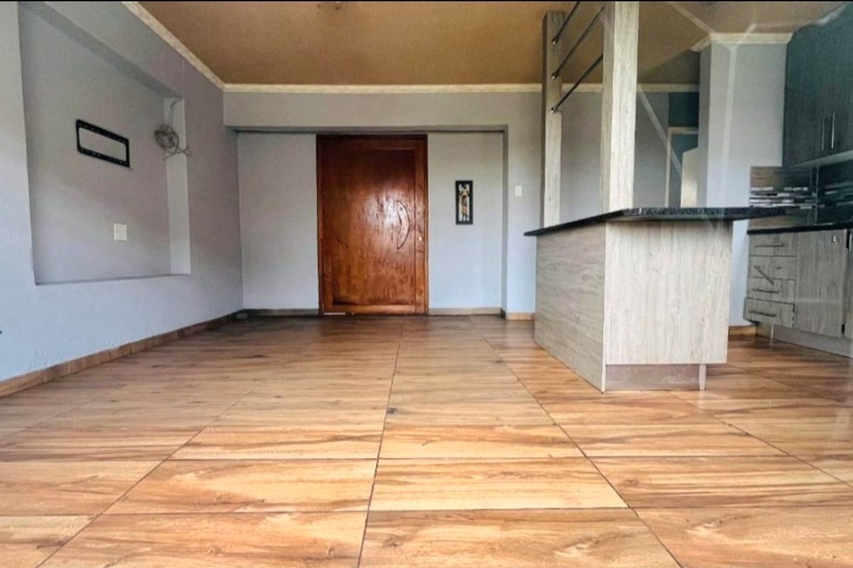 Open plan living and kitchen area featuring wood-look tiled flooring, a breakfast bar with granite countertop, and built-in kitchen cabinetry.
