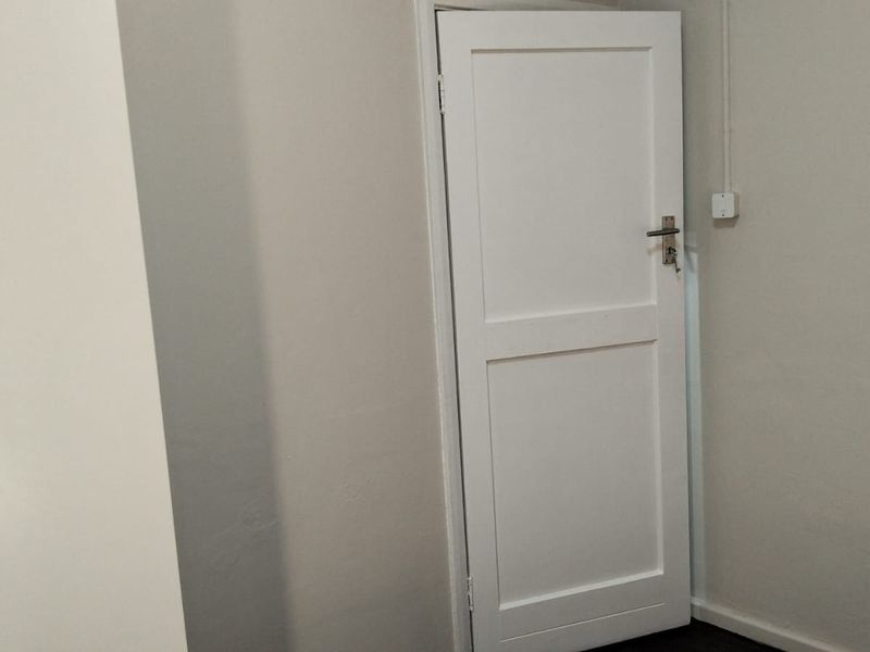 A simple interior space featuring a white internal door and built-in cupboard storage.