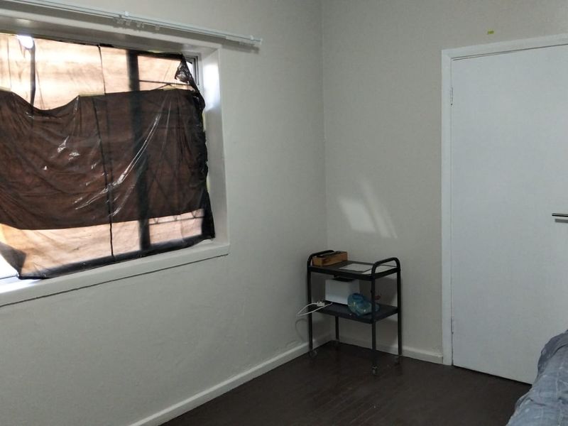 A simple, vacant bedroom featuring laminate flooring and a standard window, currently requiring cosmetic updates and new window treatments.