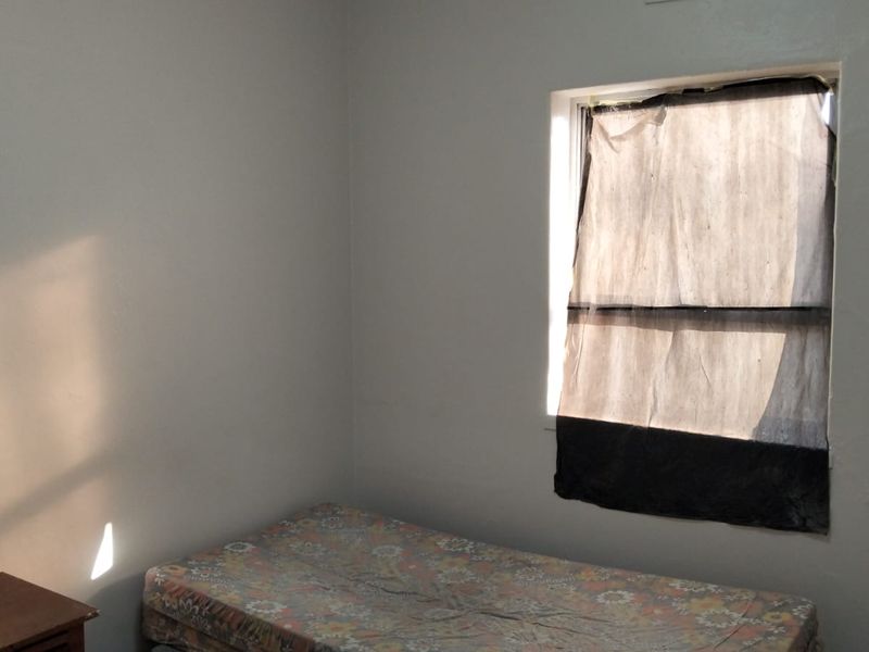 A simple bedroom featuring neutral walls and natural light, providing a blank canvas for potential interior design updates.