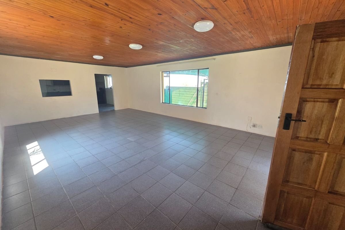 Spacious, empty living area featuring tiled flooring and a distinctive wooden tongue and groove ceiling, offering a blank canvas for interior design.