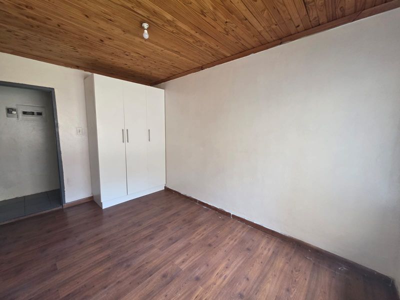 A vacant bedroom featuring laminate flooring, a timber-clad ceiling, and a built-in white wardrobe.
