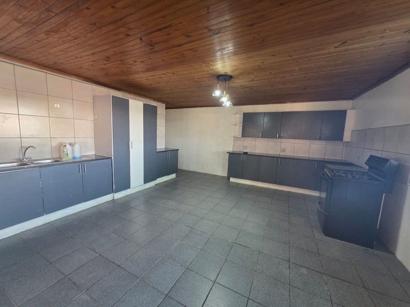 Spacious kitchen featuring dark grey built-in cabinetry, tiled flooring, a double sink, and a timber-clad ceiling.