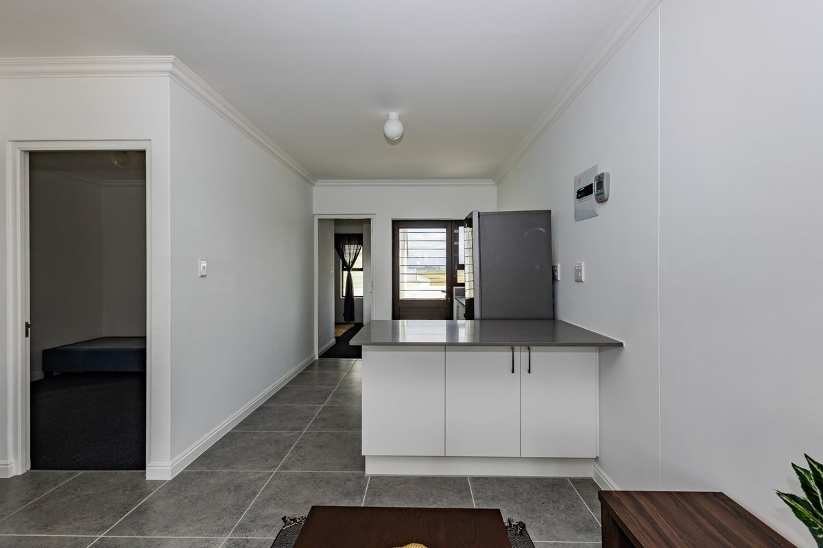 A clean, modern kitchen area featuring white cabinetry, stone countertops, and neutral tiled flooring, providing a functional and well-maintained space.