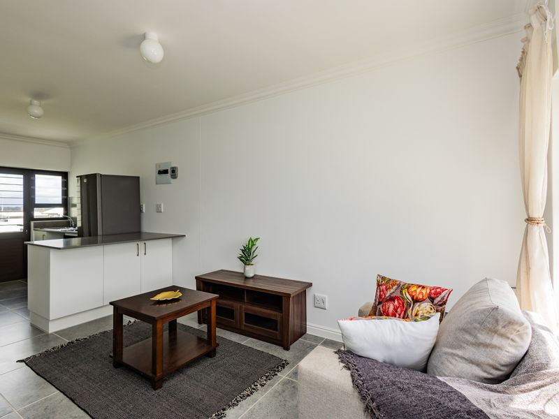 Open plan living area featuring tiled flooring, coved cornicing, and a compact kitchen with modern cabinetry and stone countertops.