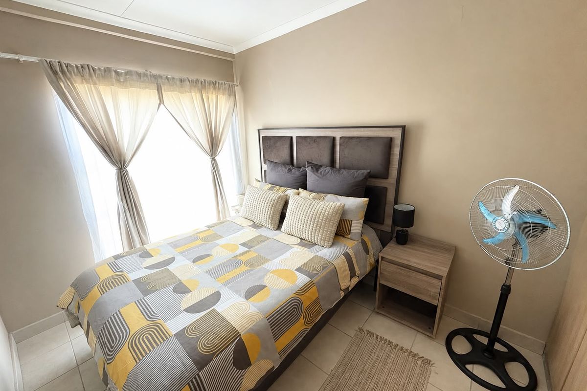 A well-lit bedroom featuring neutral wall tones, tiled flooring, and a classic cove cornice finish.