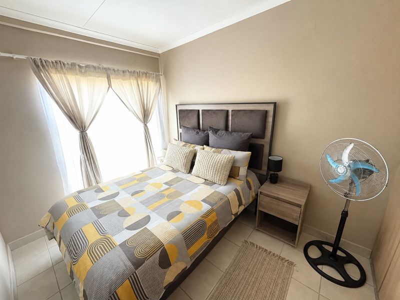A well-lit bedroom featuring neutral wall tones, tiled flooring, and a classic cove cornice finish.