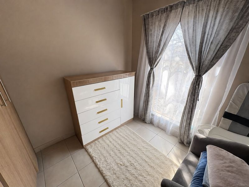 A well-lit bedroom featuring neutral tiled flooring and a built-in cupboard, offering a clean and functional living space.