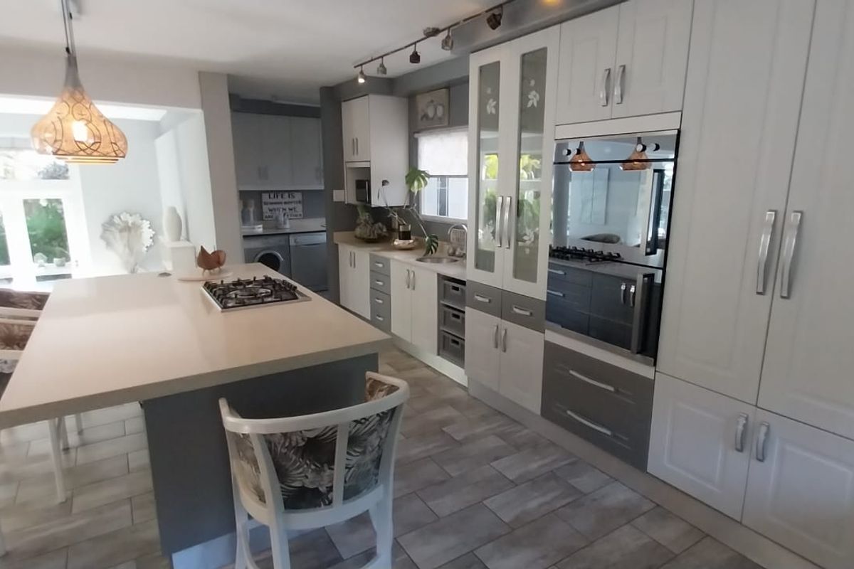 Modern kitchen featuring a central island with a gas hob, integrated cabinetry, built-in oven, and tiled flooring, offering a functional and well-maintained cooking space.