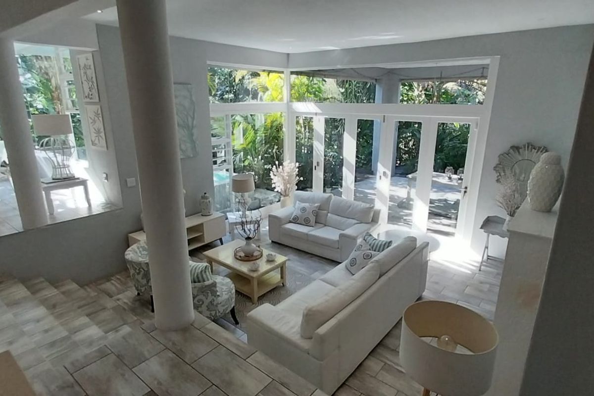 Spacious sunken living room featuring large glass sliding doors, tiled flooring, and a stone feature wall, offering seamless access to the outdoor area.