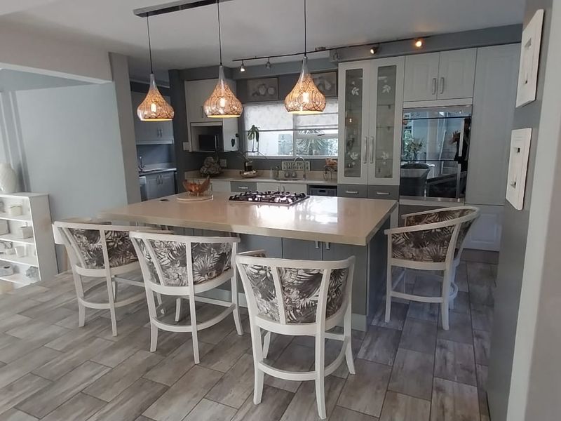 Open-plan kitchen featuring a central island with a gas hob, modern cabinetry, and stylish pendant lighting, seamlessly integrated with the living area.