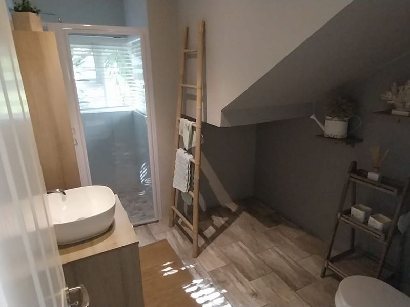 A compact bathroom featuring a modern vessel sink, vanity cabinet, and a separate shower enclosure with tiled flooring under a sloped ceiling.
