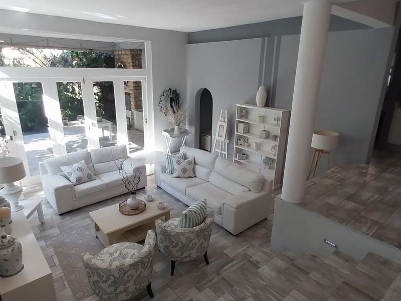 Spacious open-plan living area featuring tiled floors, a raised kitchen platform, and large bi-fold doors providing seamless access to the outdoor patio.