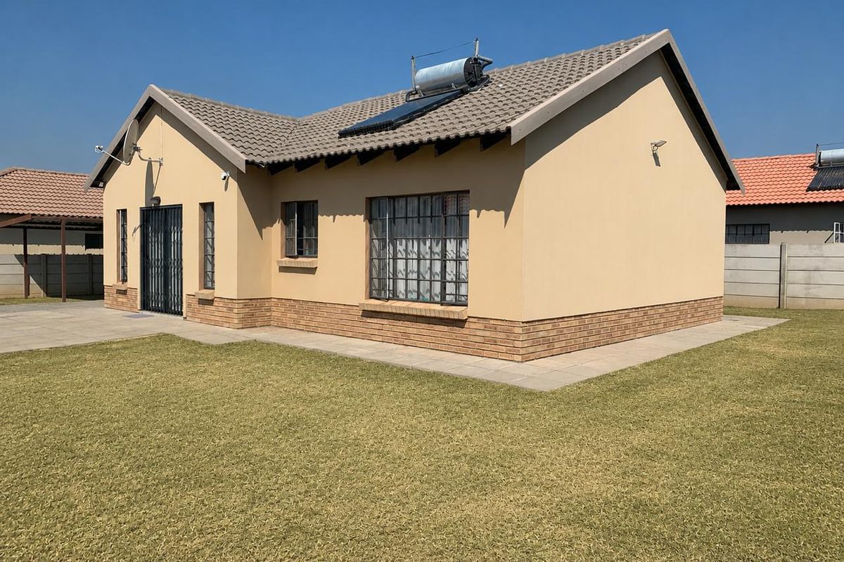 Rear view of a well-maintained single-story house featuring a tiled roof, solar geyser, and a neat surrounding lawn with paved pathways.