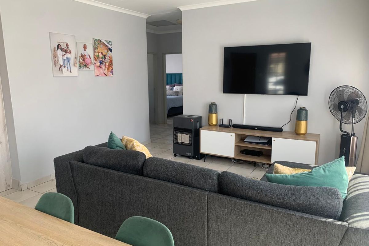 A functional living room featuring neutral wall finishes, tiled flooring, and a coved ceiling, providing a comfortable and well-maintained living space.