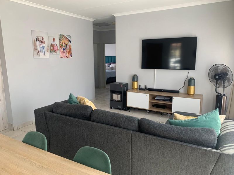 A functional living room featuring neutral wall finishes, tiled flooring, and a coved ceiling, providing a comfortable and well-maintained living space.