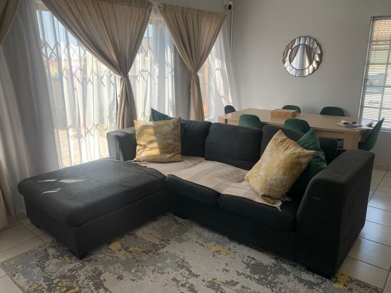 An open-plan living and dining area featuring tiled flooring and large windows with security gates, providing a bright and functional living space.
