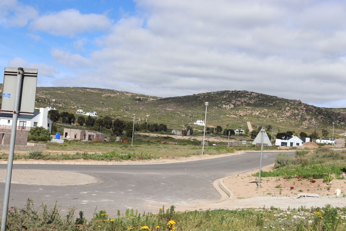 A view of the paved street and surrounding residential landscape in a developing coastal estate.