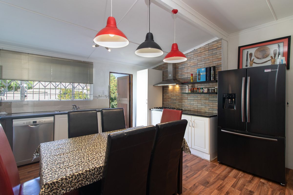 Kitchen featuring white cabinetry, a brick feature wall, laminate flooring, and built-in appliances, with direct access to the exterior.