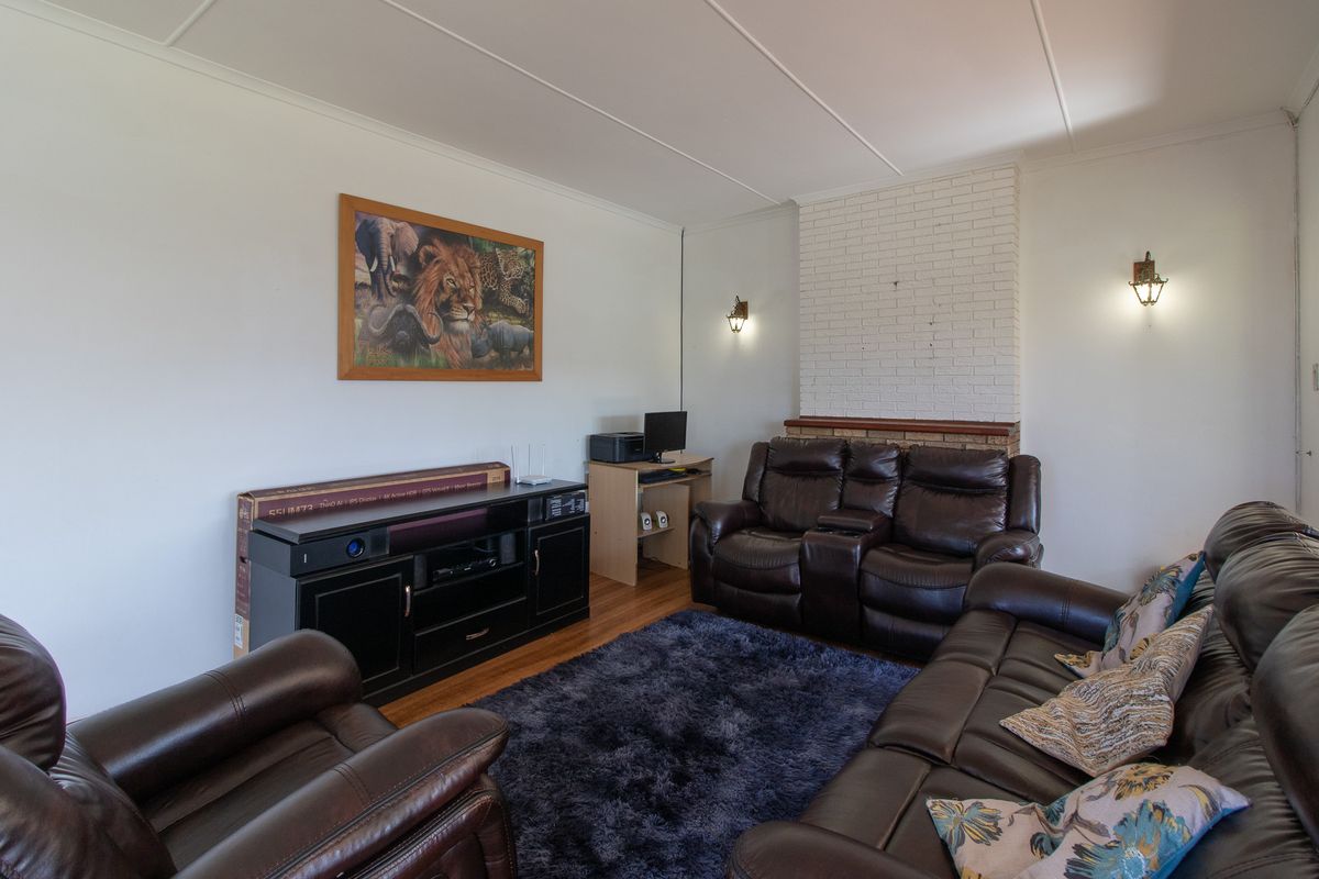 A comfortable living room featuring a classic brick fireplace, warm hardwood flooring, and wall-mounted lighting fixtures.