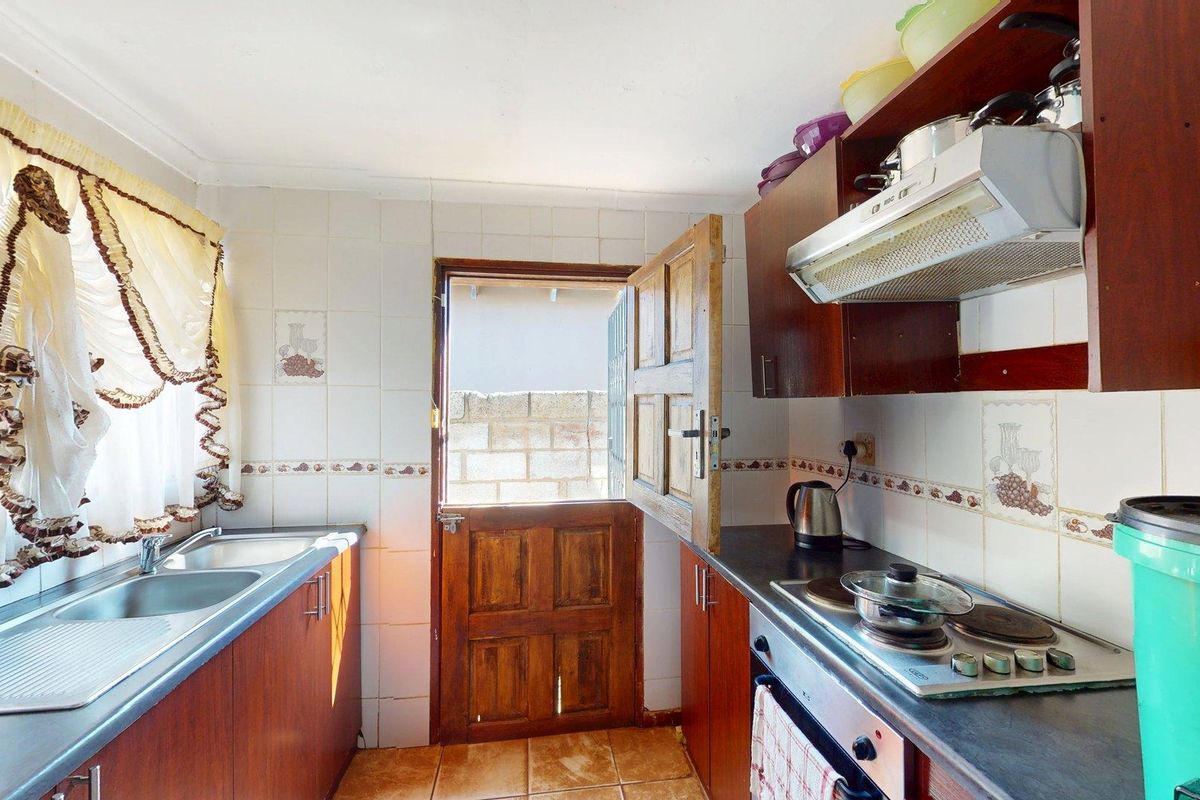 A functional kitchen featuring built-in cabinetry, a double sink, electric hob, oven, and a stable door leading to the exterior.