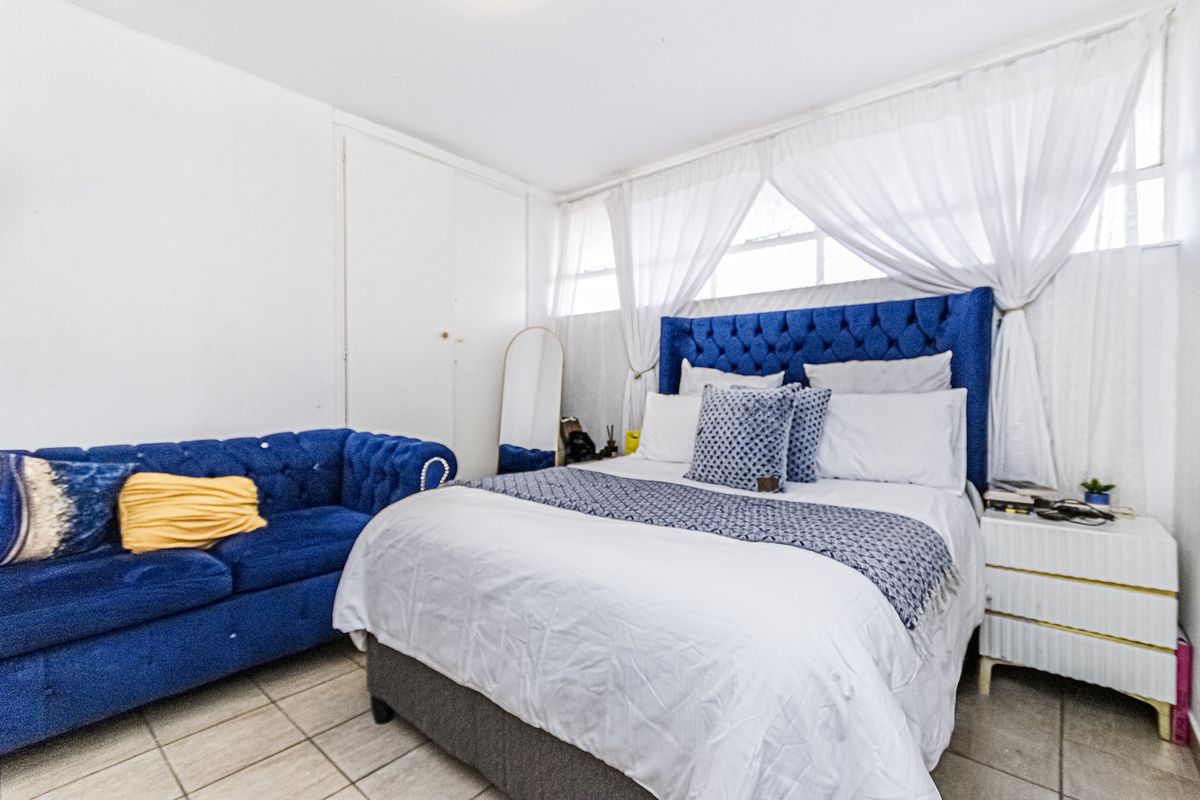 A bedroom featuring tiled flooring and a built-in wardrobe, offering a functional space with natural light.