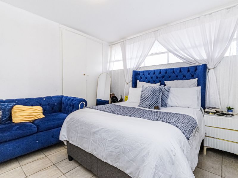 A bedroom featuring tiled flooring and a built-in wardrobe, offering a functional space with natural light.
