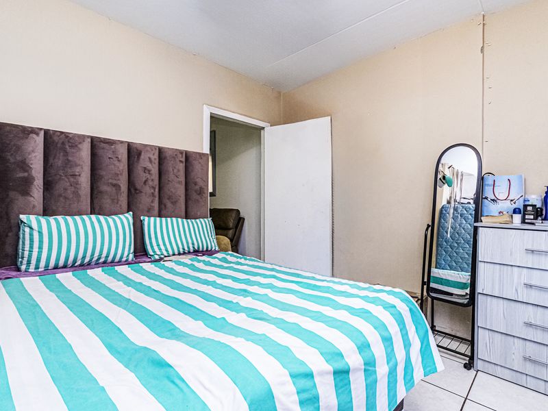A bedroom featuring tiled flooring and neutral wall finishes, providing a functional space ready for cosmetic updates and personalization.