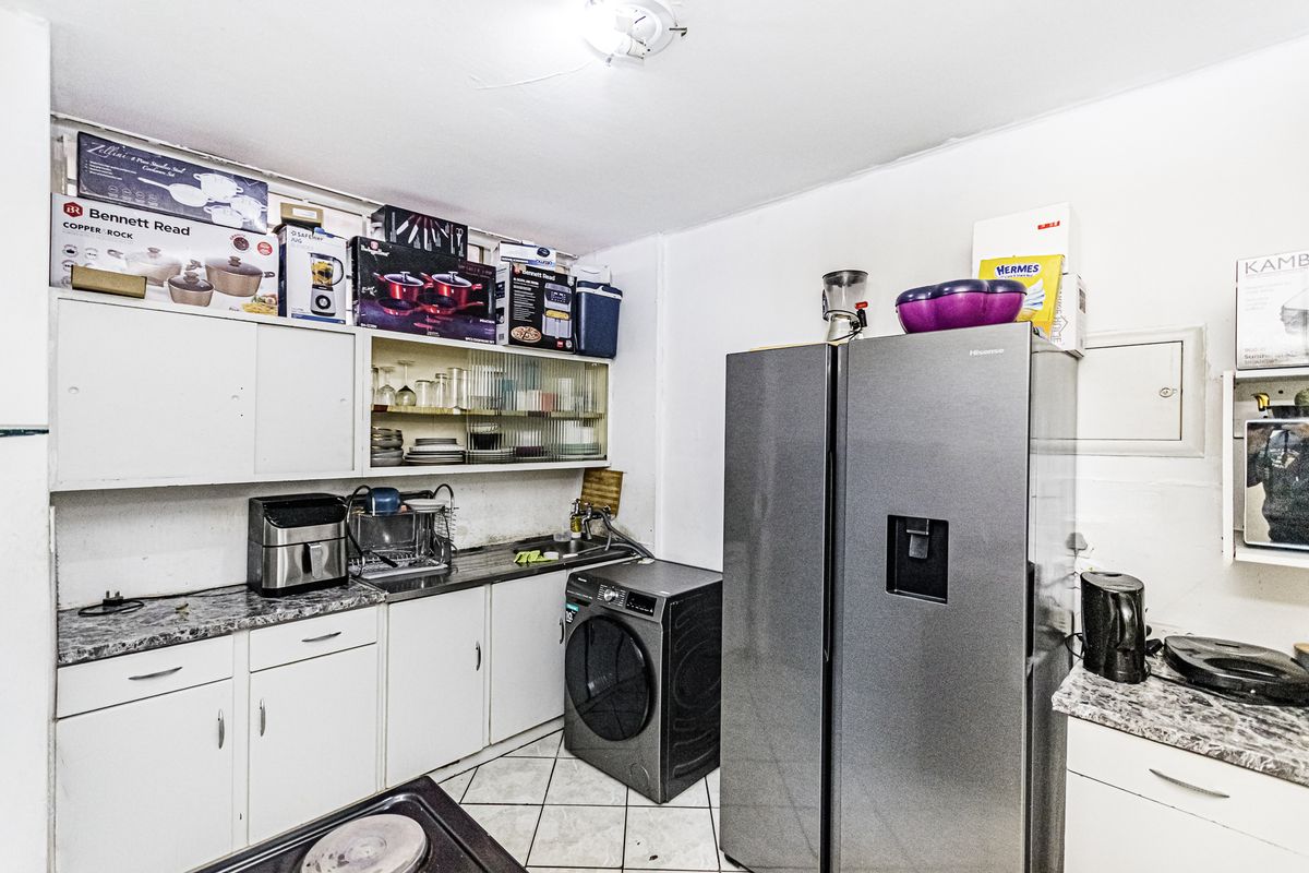Compact kitchen area featuring built-in cabinetry, laminate countertops, and tiled flooring, providing essential utility space for the apartment.
