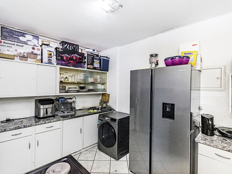 Compact kitchen area featuring built-in cabinetry, laminate countertops, and tiled flooring, providing essential utility space for the apartment.