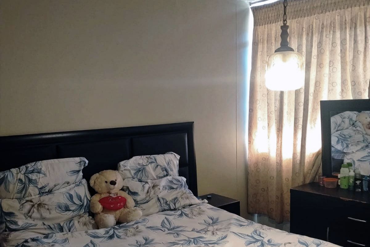 A bedroom featuring a pendant light fixture and window curtains.