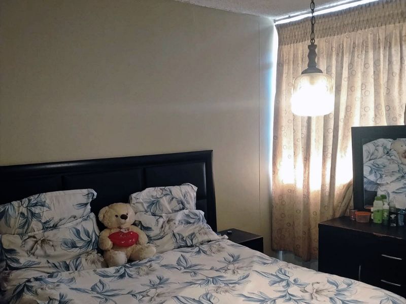 A bedroom featuring a pendant light fixture and window curtains.