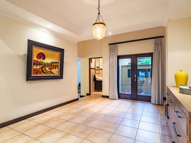 Spacious entry hall featuring tiled flooring, crown molding, elegant pendant lighting, and double glass doors providing access to an outdoor area.