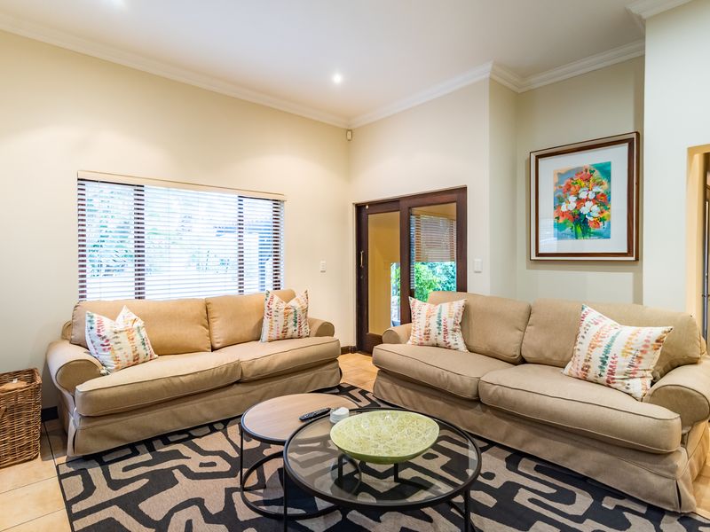 A well-maintained living room featuring tiled flooring, crown molding, recessed lighting, and a sliding glass door providing access to the exterior.