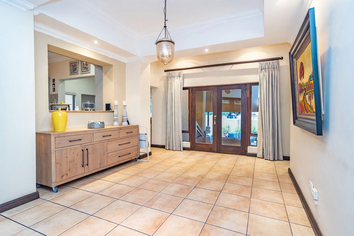 A bright living area featuring tiled flooring, a decorative ceiling with cove molding, and french doors providing access to the outdoor space.