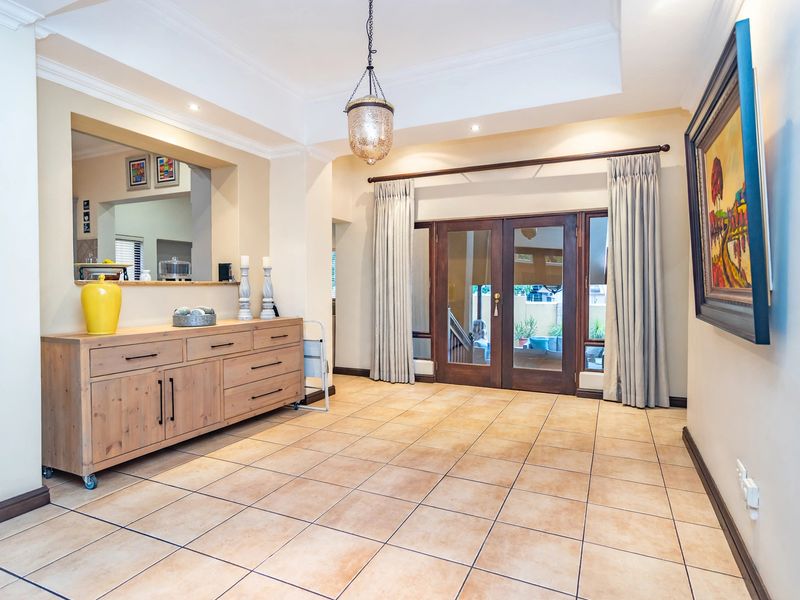 A bright living area featuring tiled flooring, a decorative ceiling with cove molding, and french doors providing access to the outdoor space.
