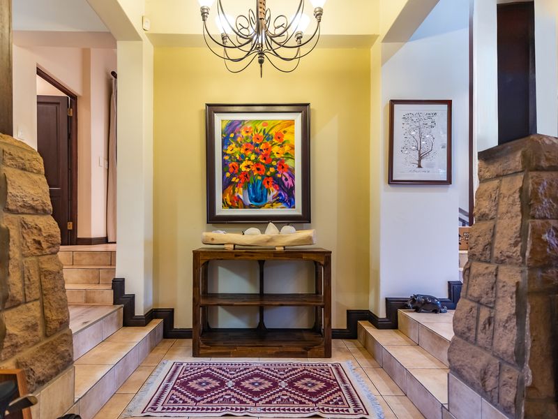 Welcoming entrance foyer featuring stone-clad pillars, tiled steps, and a decorative wrought iron chandelier.
