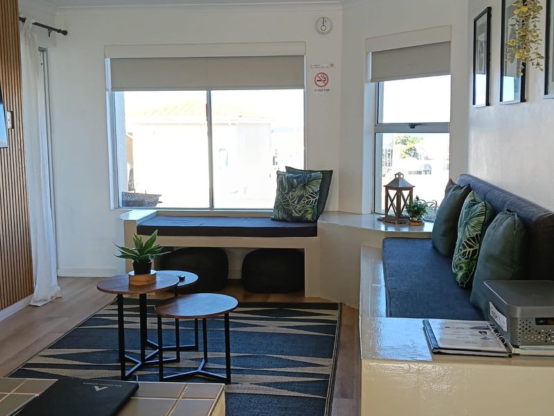 A bright living area featuring a built-in window seat, modern laminate flooring, and decorative slat wall paneling, offering a comfortable and functional space.