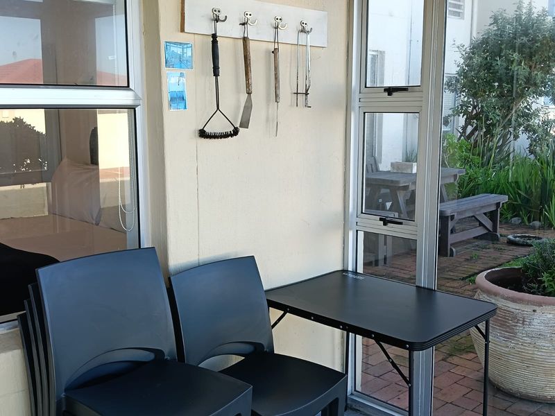 A covered patio area featuring aluminium window frames and access to an outdoor paved garden space.