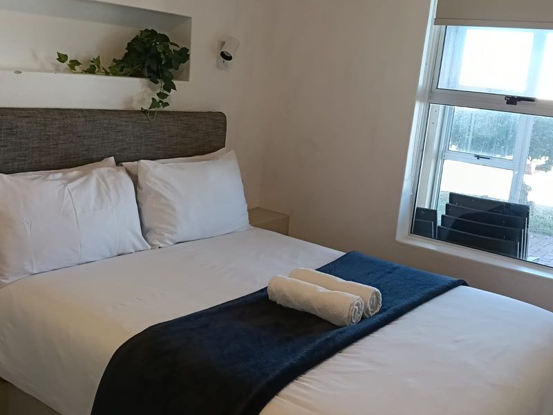 A cozy bedroom featuring a built-in wall niche, a sliding window for natural light, and a wall-mounted reading light.